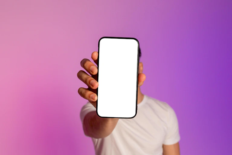 Photo of a young man holding up a phone with a pure white screen to the camera.