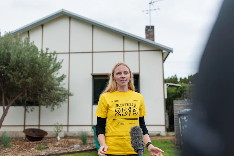Laura Scalafiotti, Thirroul resident standing in front of a house wearing a bright yellow Electrify 2515 t-shirt