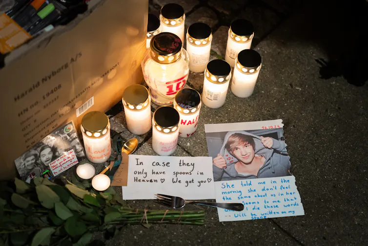 Lit candles and photos with messages to Payne