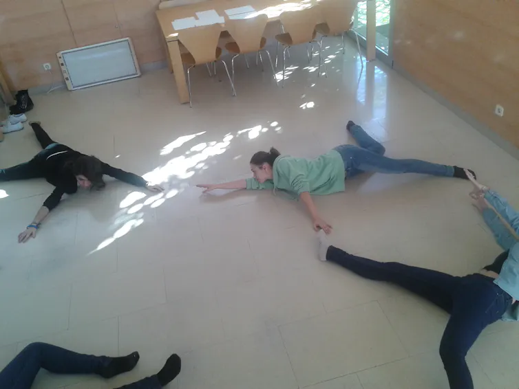 Varios adultos tumbados en el suelo del aula en diferentes posturas.
