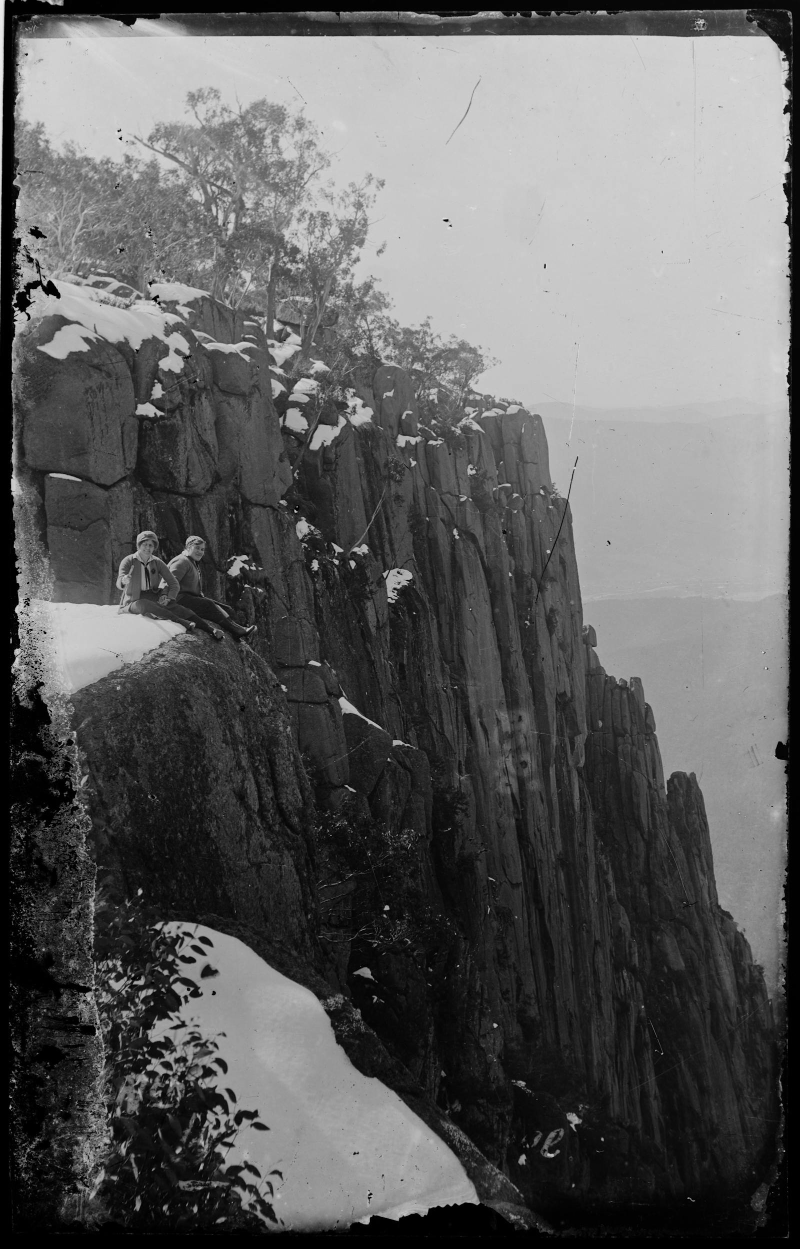 Two women sitting on edge of cliff
