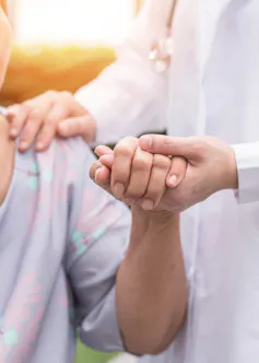 Aged care worker holding the hand of an aged care resident.