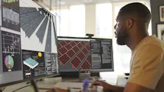 A man sits at a few computer screens planning a solar farm using computer assisted diagrams