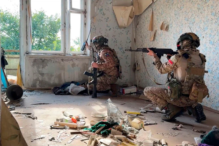 Two Russian soldiers take up a position in a damahed house.