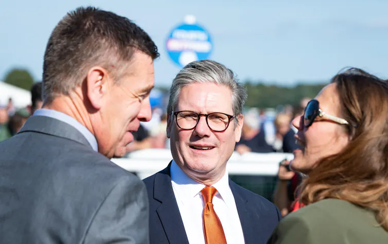 Keir Starmer and his wife talking to a man at a race track.