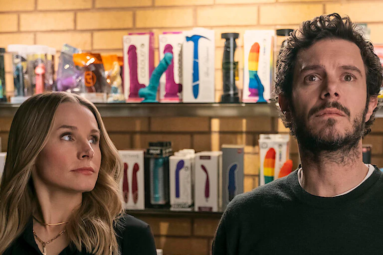 A woman and man in front of a shelf of vibrators.
