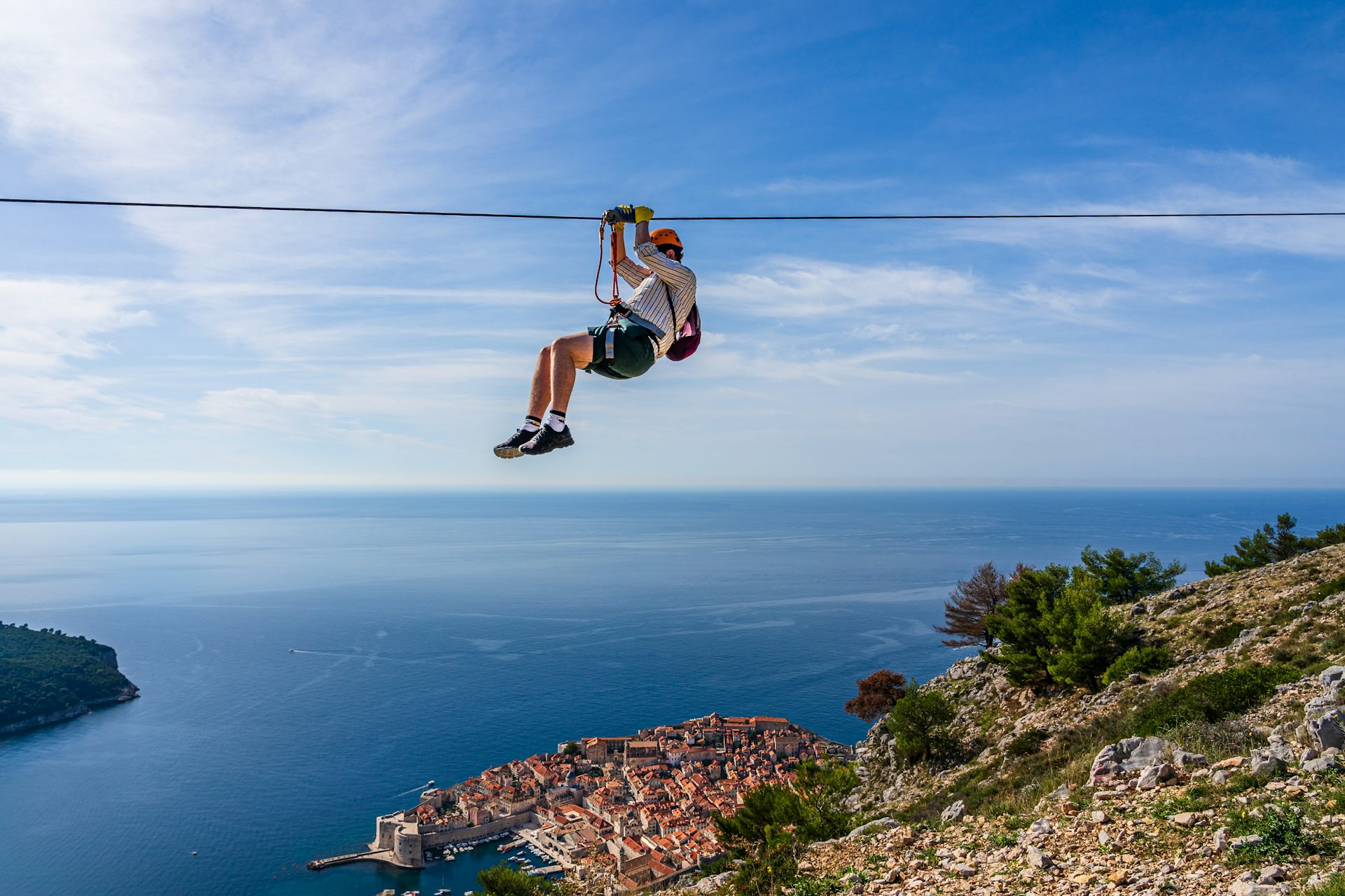 A man on a zipline above Dubrovnik old town in Croatia.