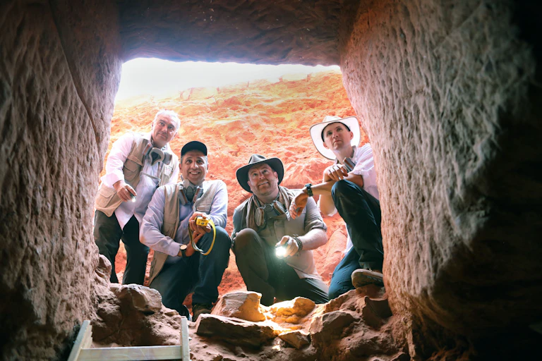 Four men lighting torches to look into the tomb