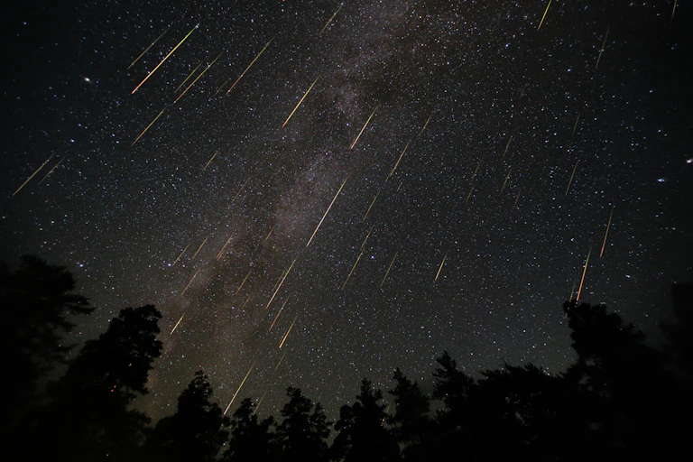 Céu noturno estrelado e repleto de meteoritos.