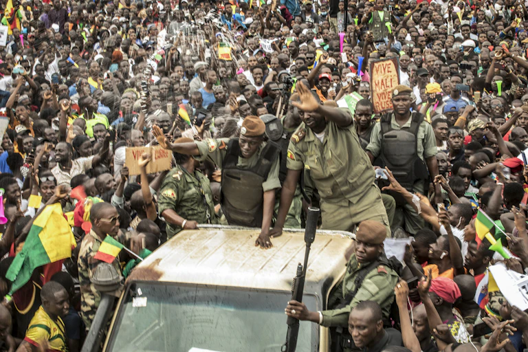 A crowd surrounds a vehicle.
