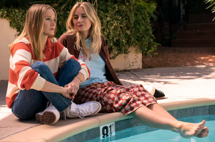 Two women next to a pool.
