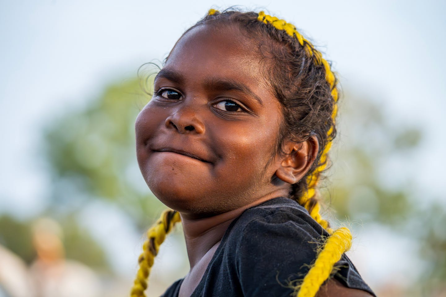 A young Aboriginal girl smiles at the camera.