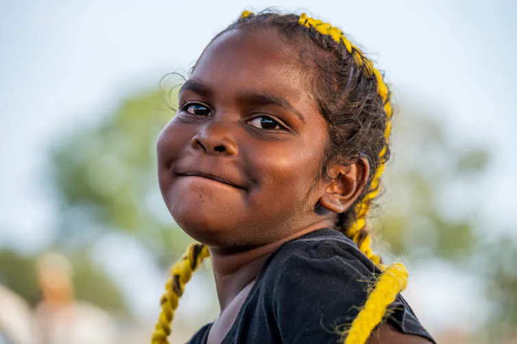 A young Aboriginal girl smiles at the camera.