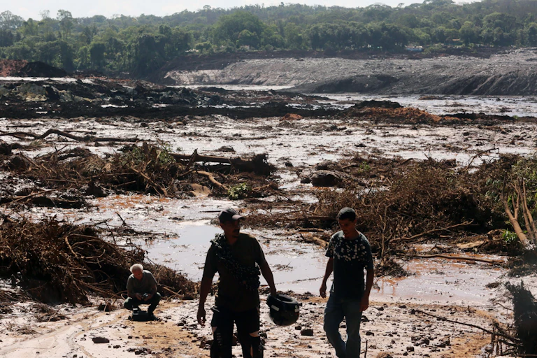 Two men walking across a muddy landscape