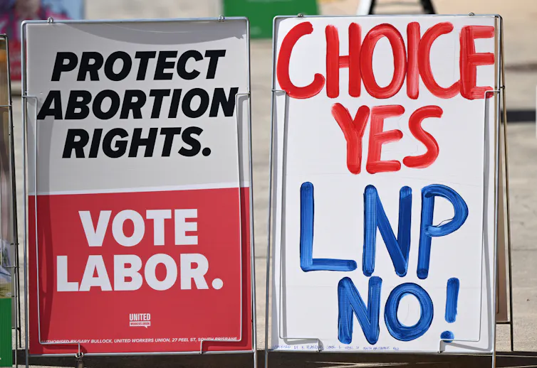 Two election signs, one saying Protect Abortion Rights, Vote Labor, the other saying Vote Yes, LNP No.