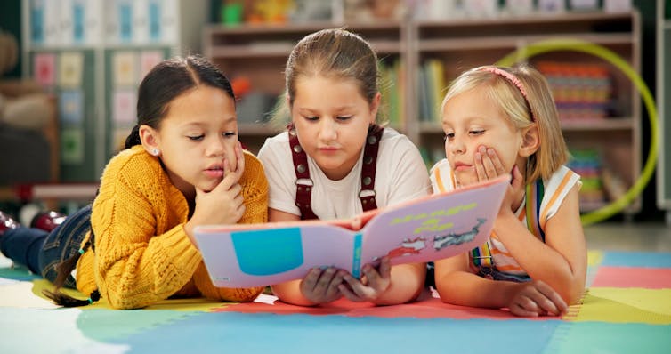 Three young girls reading a picture book