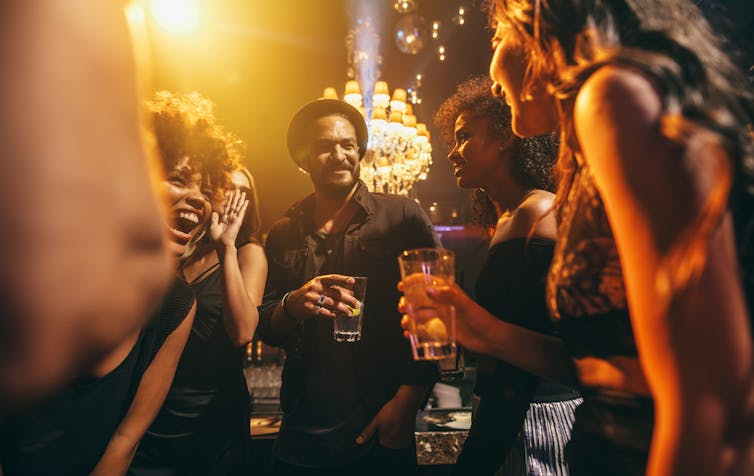 group of people chatting and laughing in club or party setting at night