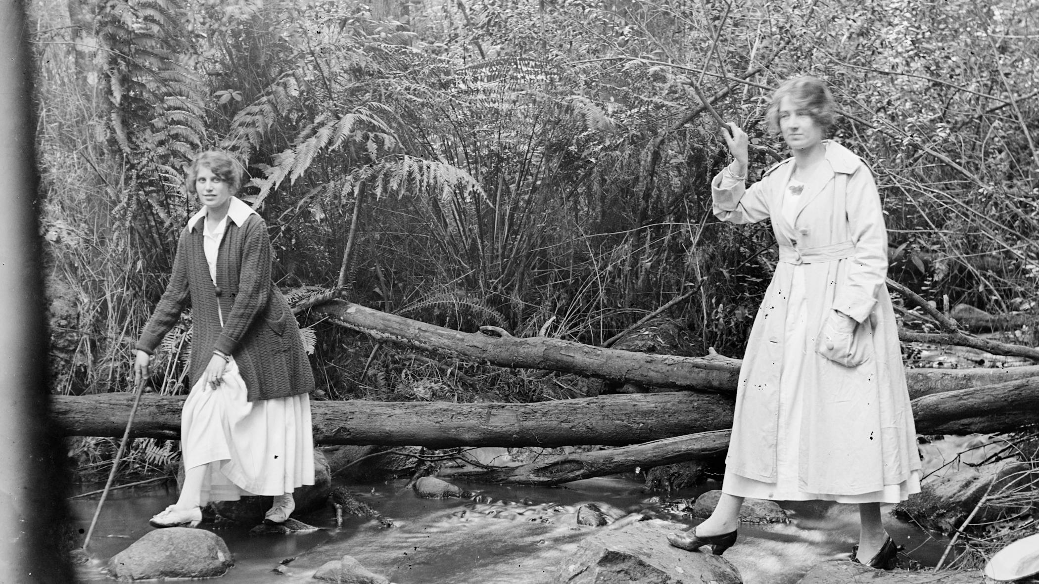Bushwalking women crossing a creek in long skirts