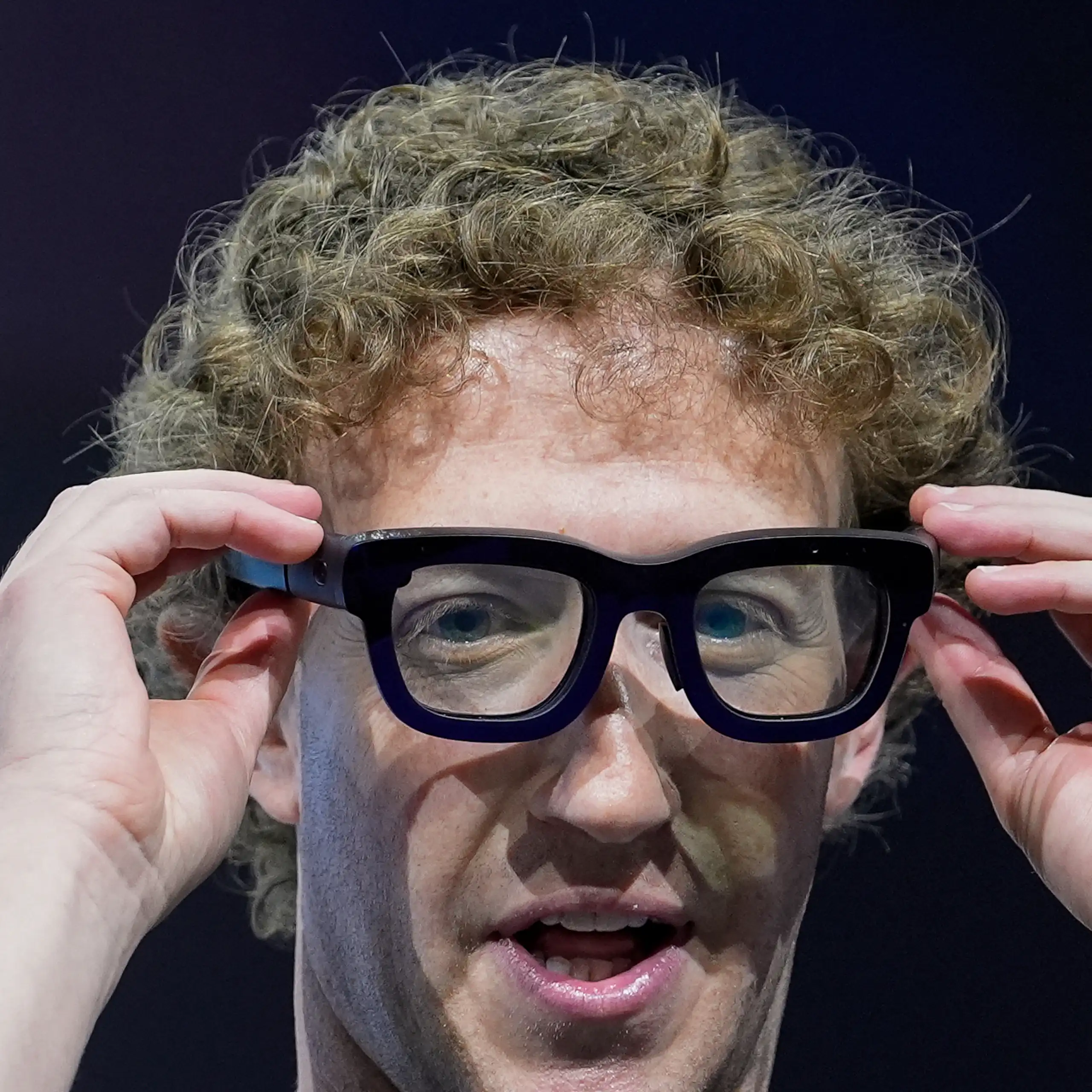 Seorang pria mengenakan kacamata augmented reality dengan bingkai hitam tebal.