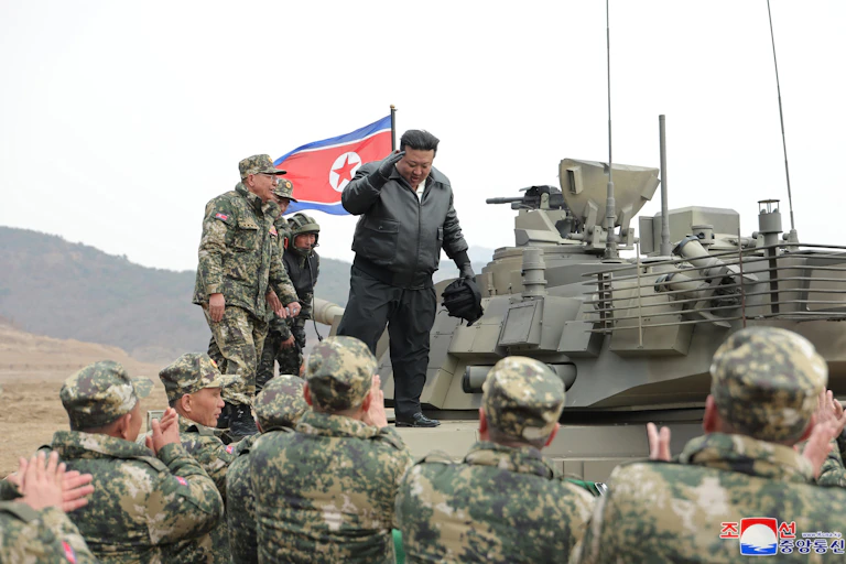 North Korean leader Kim Jong-un stands on a tank as troops applaud, March 2024.