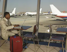A man works on a laptop in the airport