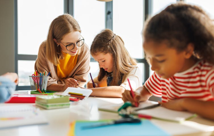 Teacher helping pupil in class