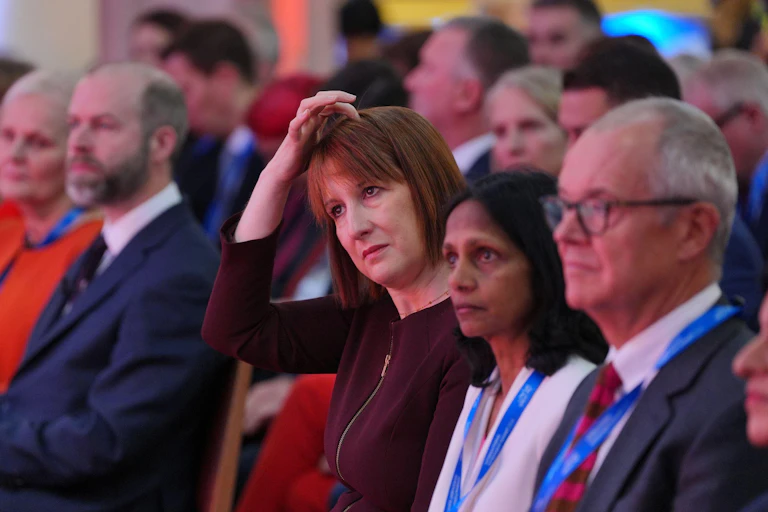 Uk chancellor scratching her head in the audience of the UK investment summit