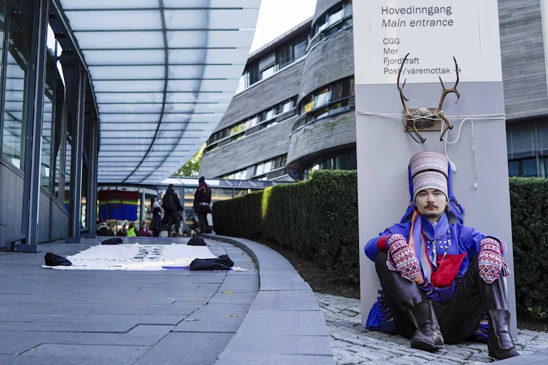 Man in traditional dress sits outside office