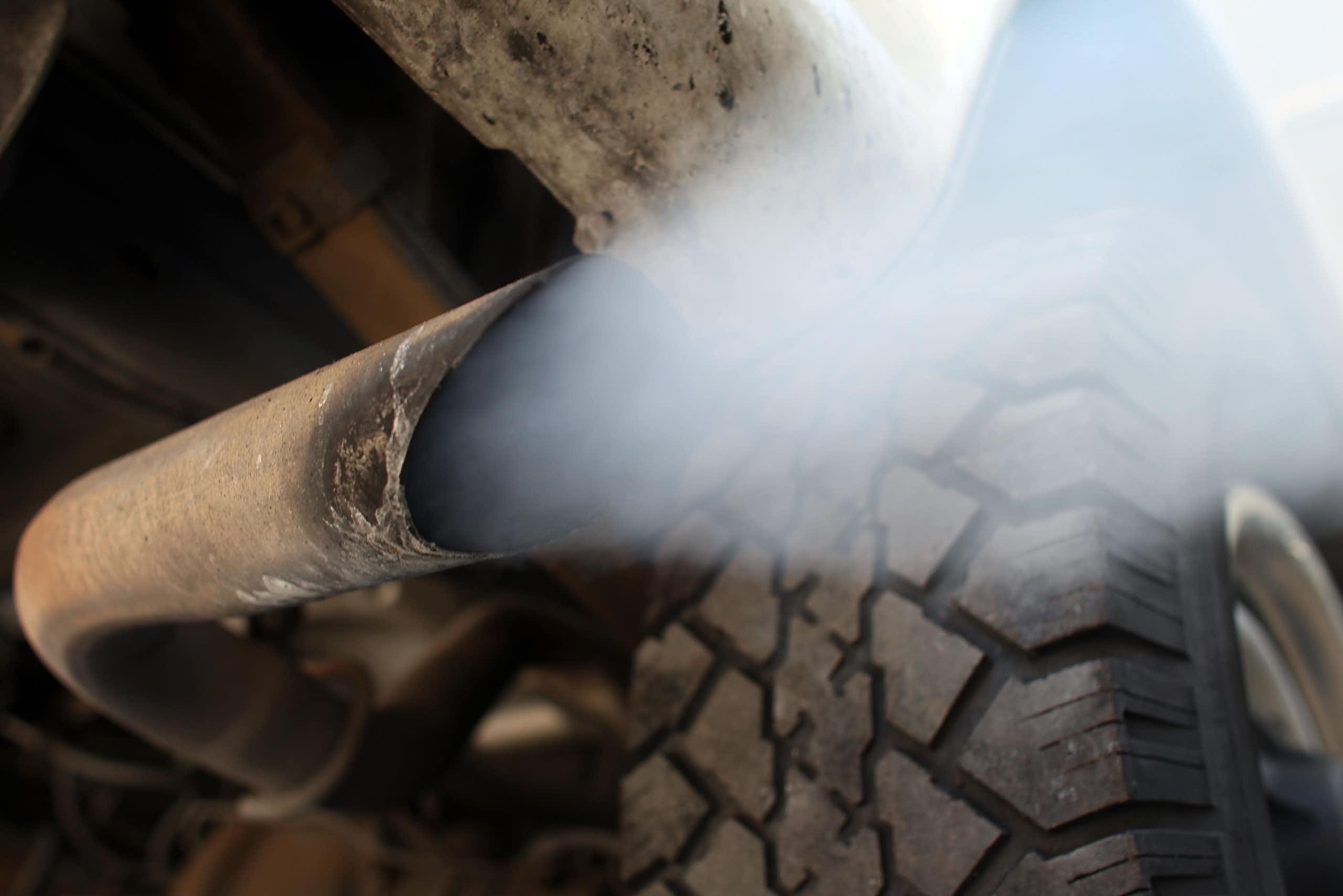 Back view of vehicle exhaust flowing out of the tailpipe.
