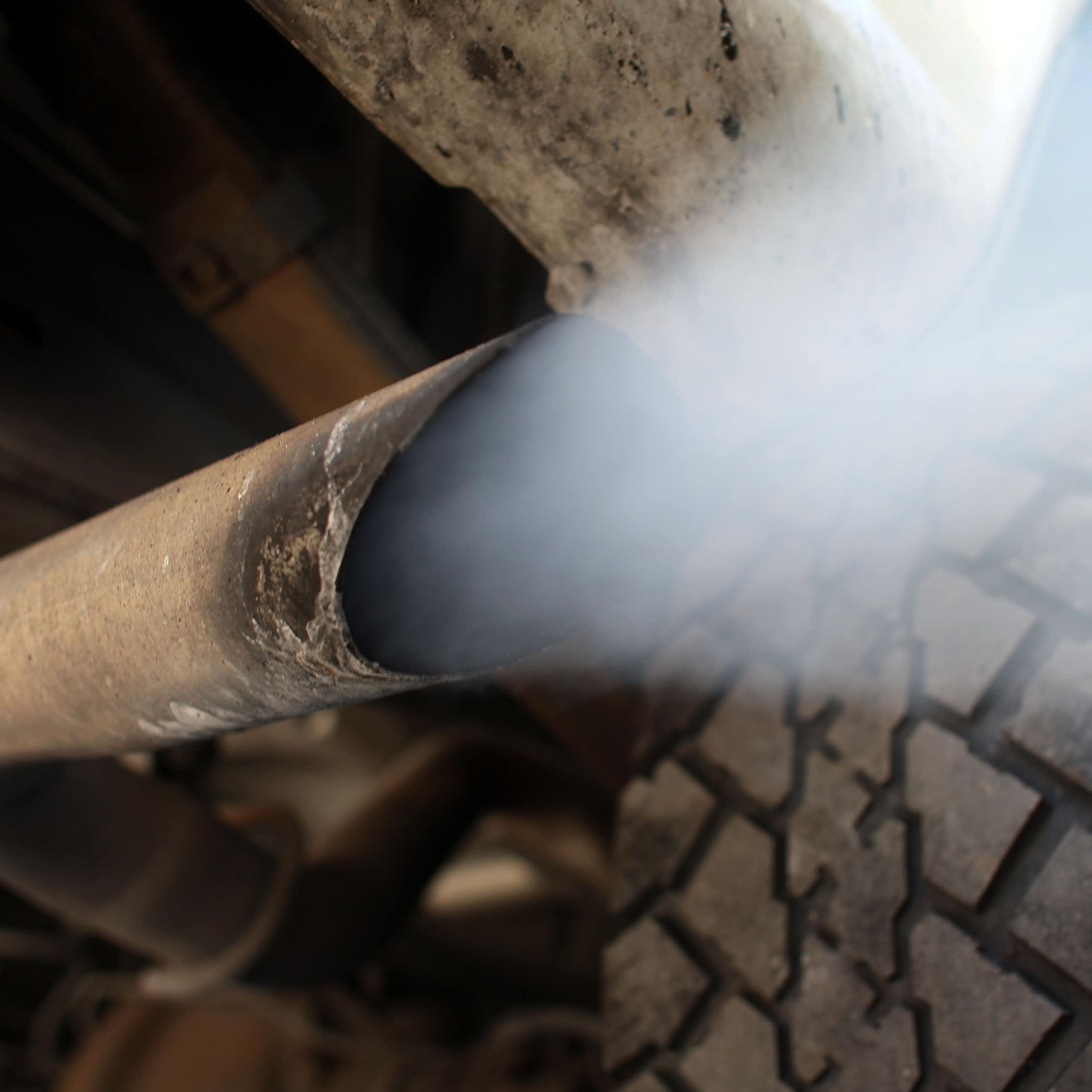 Back view of vehicle exhaust flowing out of the tailpipe.