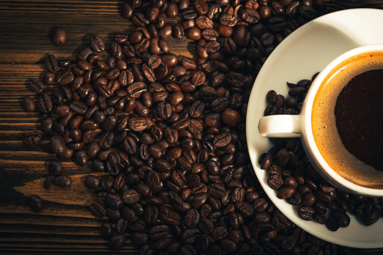 Coffee beans and cup of coffee viewed from above.