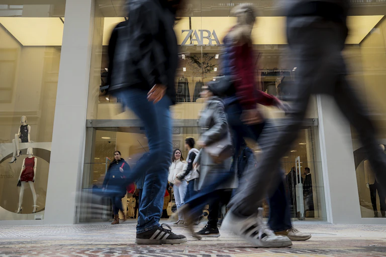 Young people walk past a large Zara store.