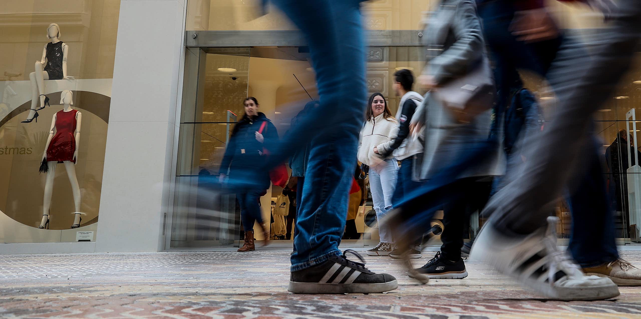 Young people walk past a large Zara store.