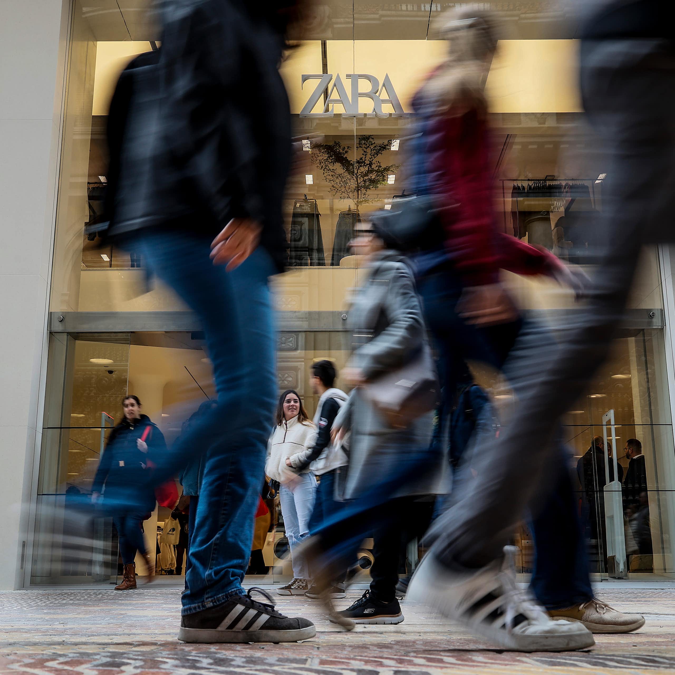 Young people walk past a large Zara store.