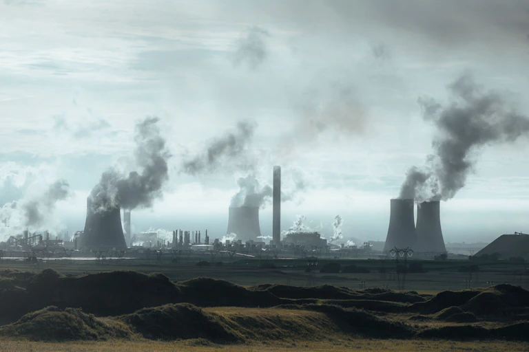A gigantic factory with coal burning towers and pollution billowing out into the sky