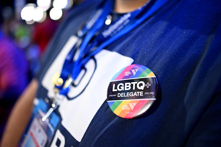 Close up shot of a rainbow pin reading 'LGBTQ+ delegate' on a blue shirt