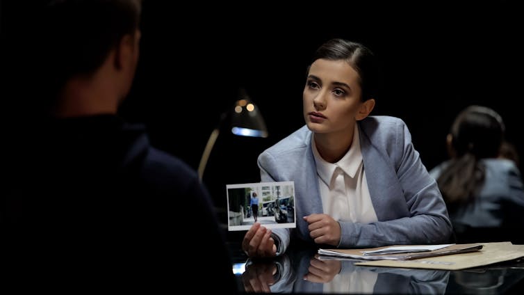 A seated woman shows a photo to a man seated in front of her