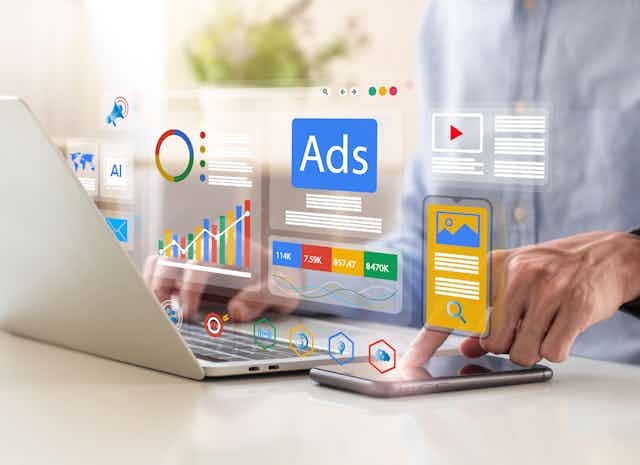 A man uses a laptop and a cellphone in a close-up photo.  A man uses a laptop and a cellphone in a close-up photo.