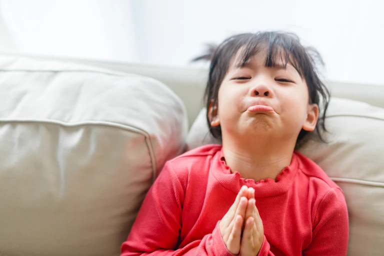 A young girls pouts and puts here hands together.