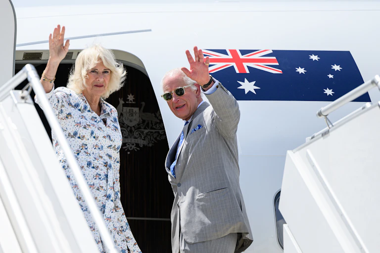 The king and queen waving as they board an aeroplane in Australia