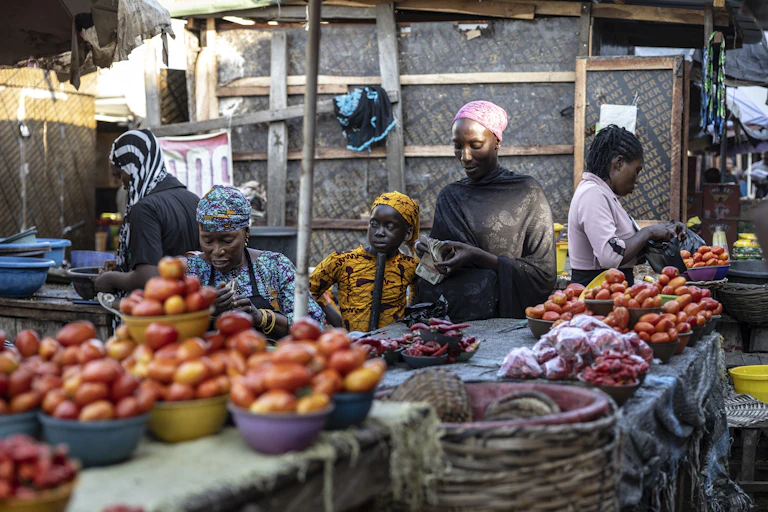 A woman counts money as other women engage in other activities