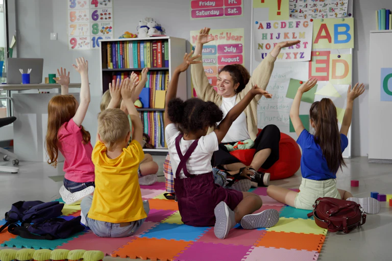 Children and teacher put hands above head