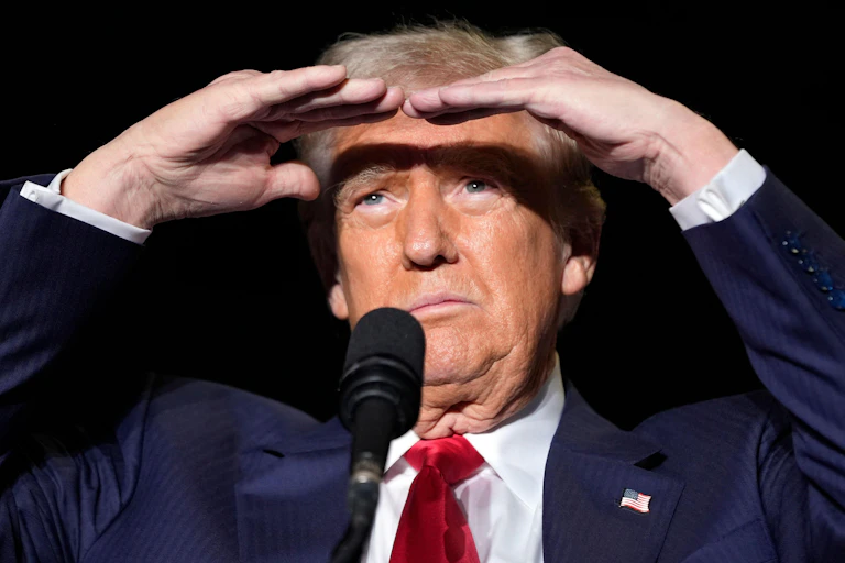 Donald Trump shielding his eyes from the sun as he looks into the distance
