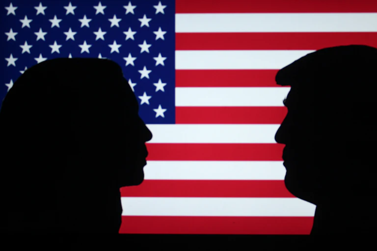 Silhouettes of Kamala Harris and Donald Trump in front of a US flag.