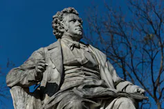 A stone statue of a man with blue sky behind him.