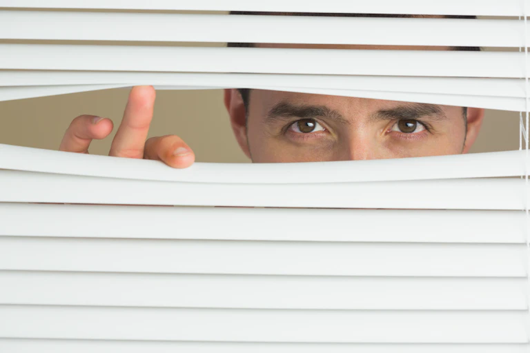 eyes peering through a venetian blind