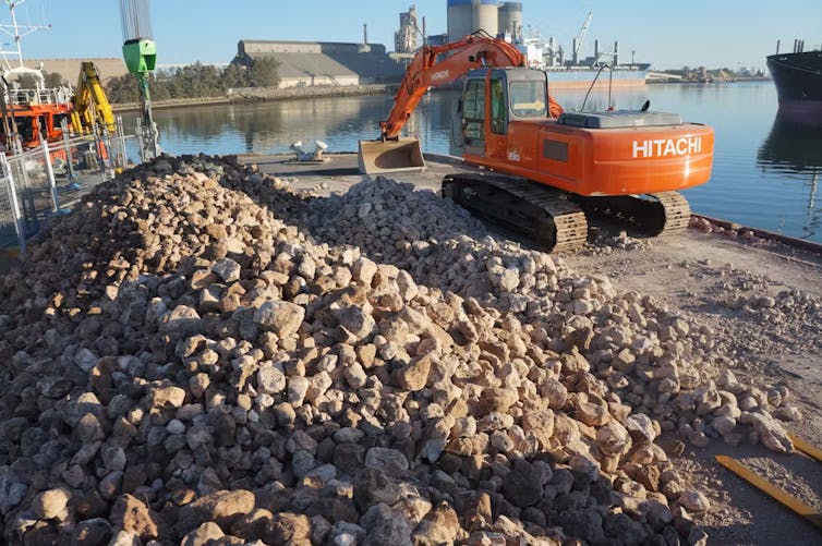excavator and limestone rocks in dock