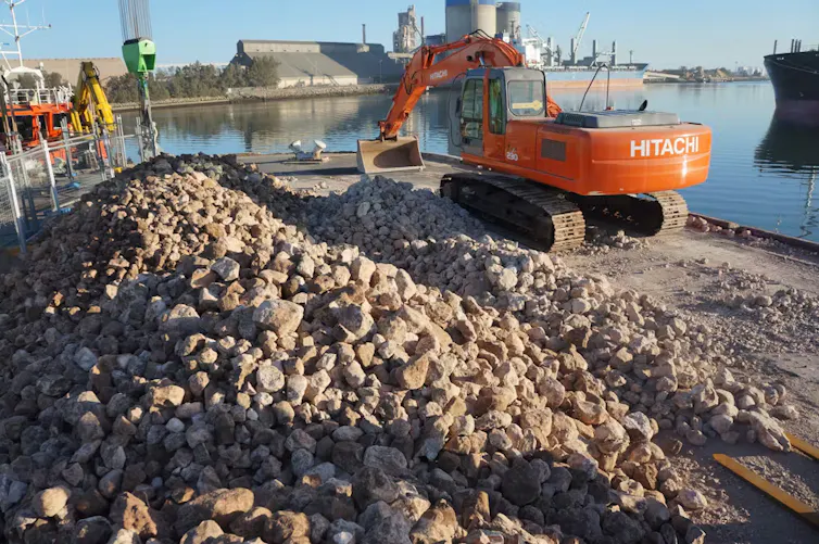 excavator and limestone rocks in dock