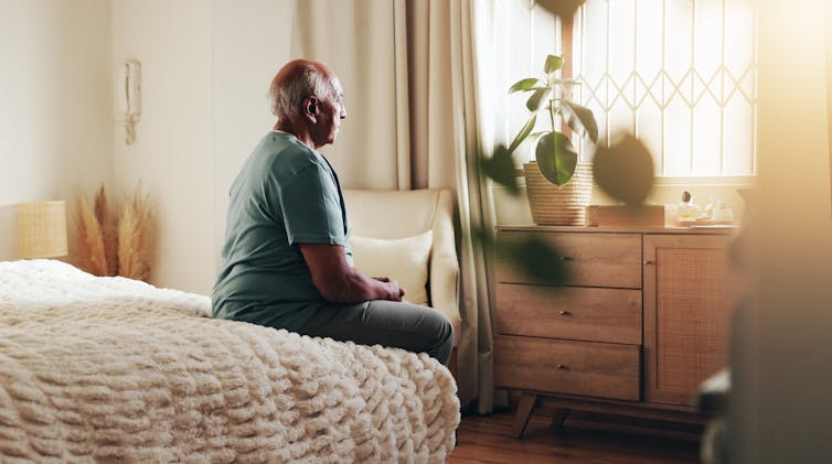 Man sits on edge of his bed