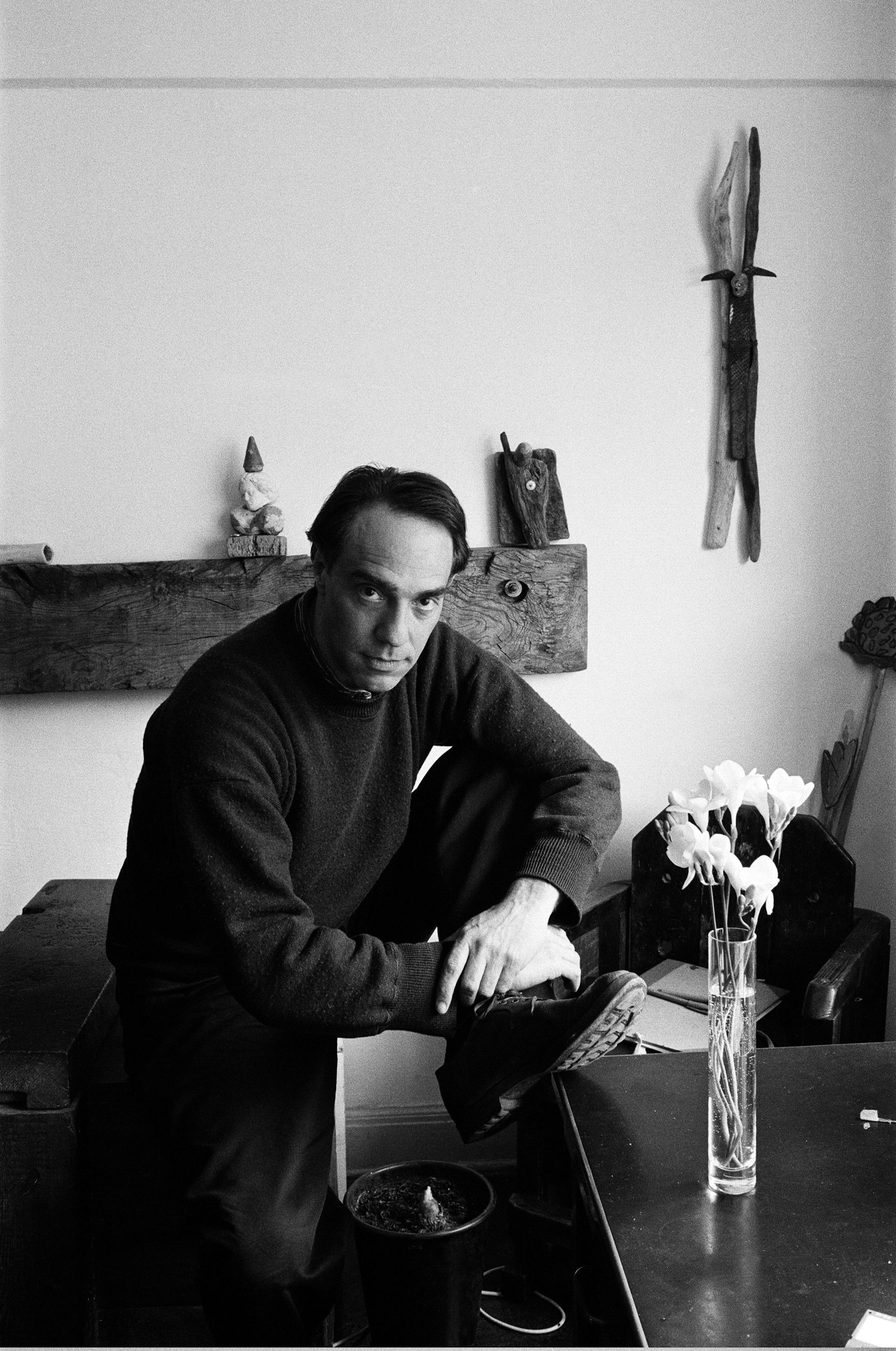 A serious young  man in his home photographed in moody black and white.